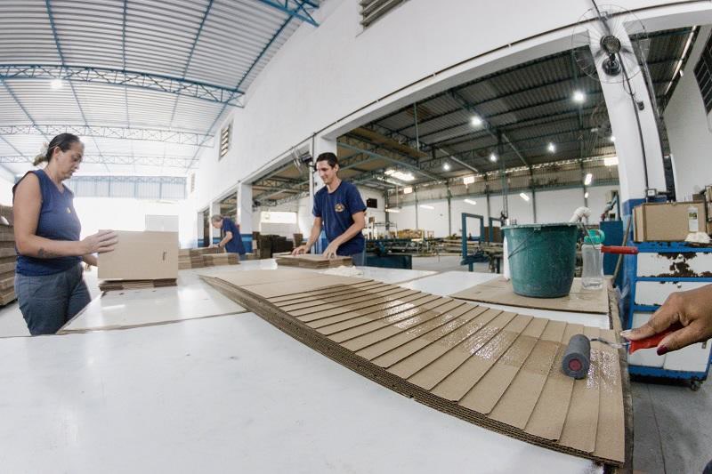 Equipe conferindo e colando chapas na mesa de produção