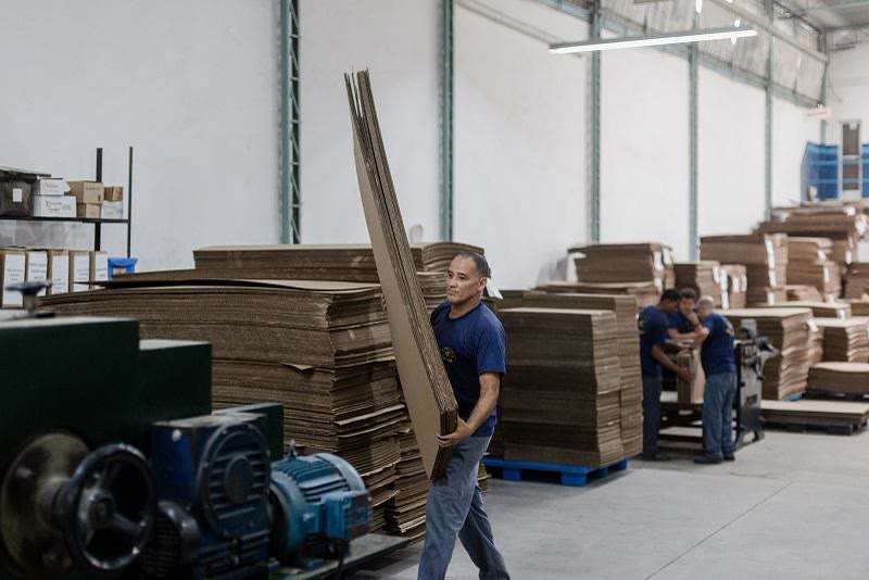 Operadores carregando fardos de caixas de papelão no caminhão da fábrica